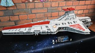 A side-on view of the Lego UCS Venator, sitting on a starry tabletop and framed against a brick wall