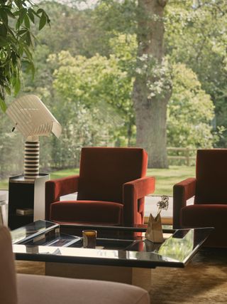 coffee table and armchairs with floor-to-ceiling view of garden