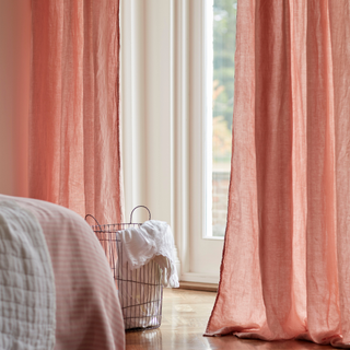 Blush pink linen curtains hung over a bedroom window