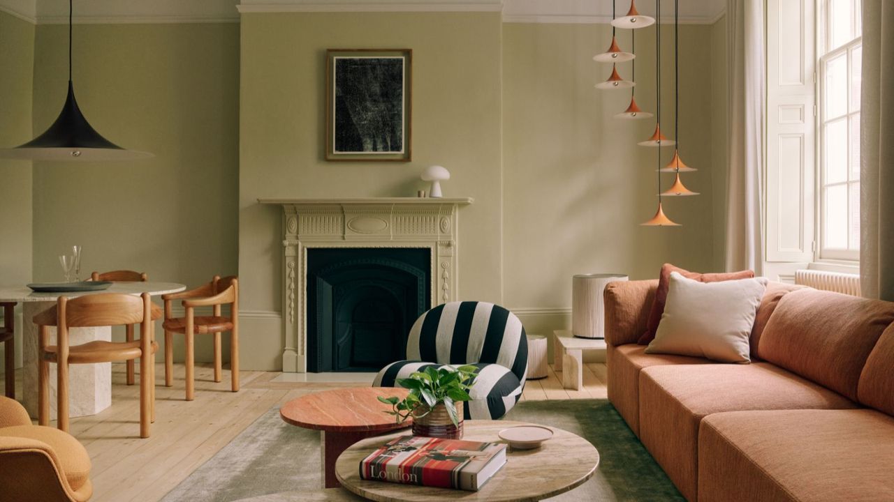 An image from the GUBI London showroom, a living room with a pink couch, black and white striped chair and a small dining room table