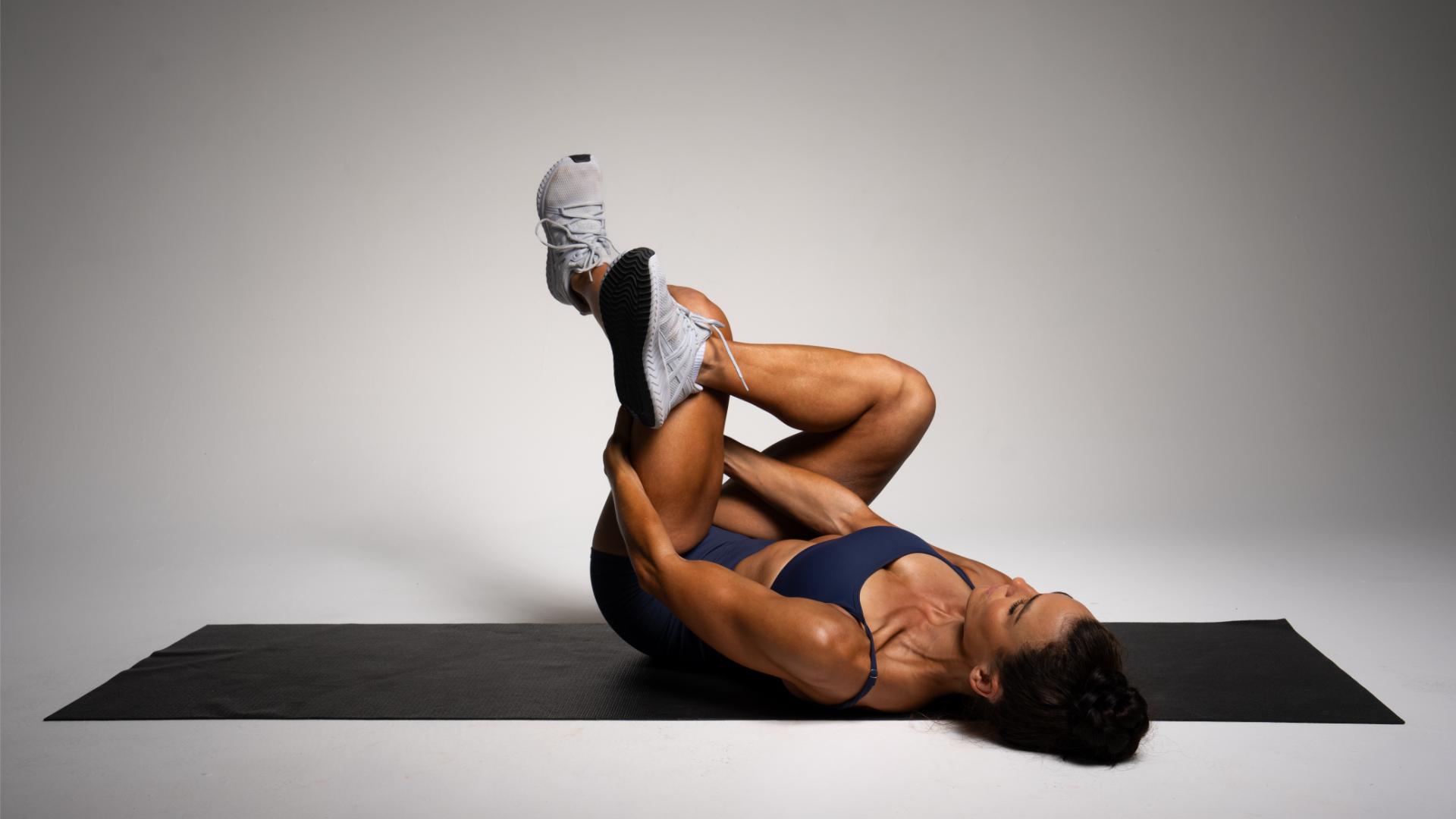 Woman in blue sportswear demonstrates a stretch against a studio background