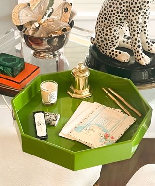 A green tray with paper, candles, and decor on it, with a leopard statue next to it