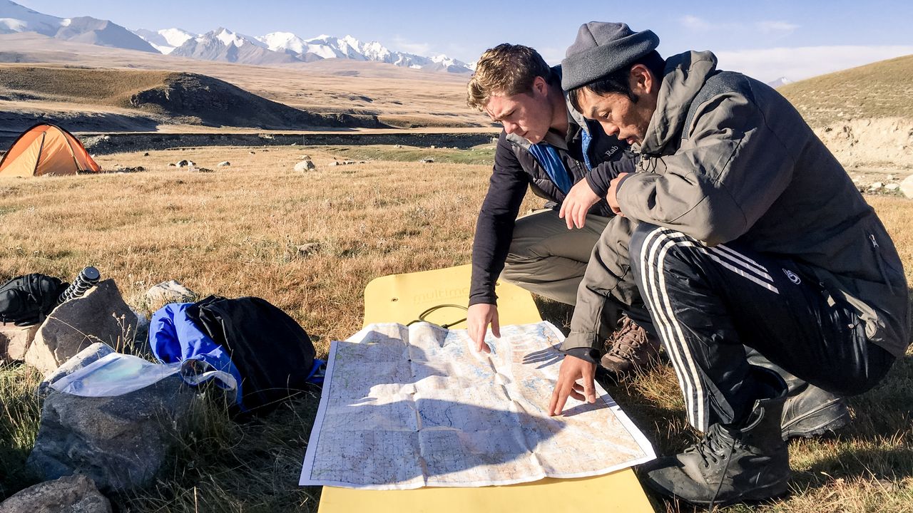 Henry and a local nomadic guide with a map, planning their route across Kyrgyzstan