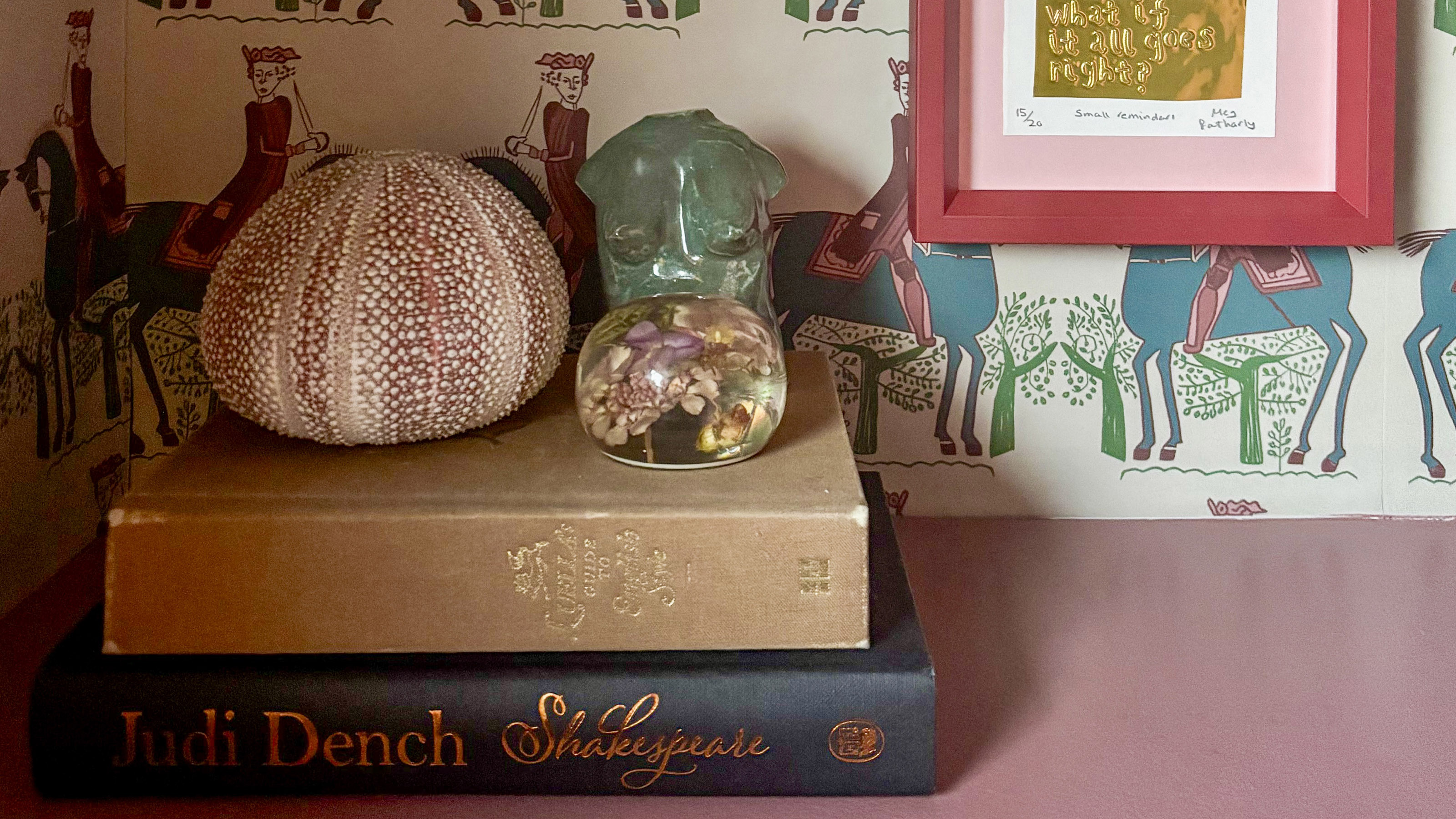 pink shelf styled with two books, a shell and some ornaments