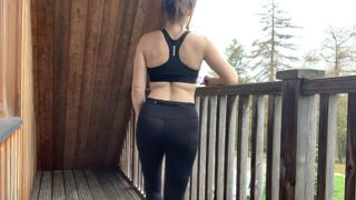 Woman standing on balcony in black sports bra