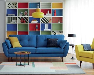 French Connection Zinc Four-seater sofa in indigo, £899, available exclusively at DFS, with colorful bookshelf storage decor