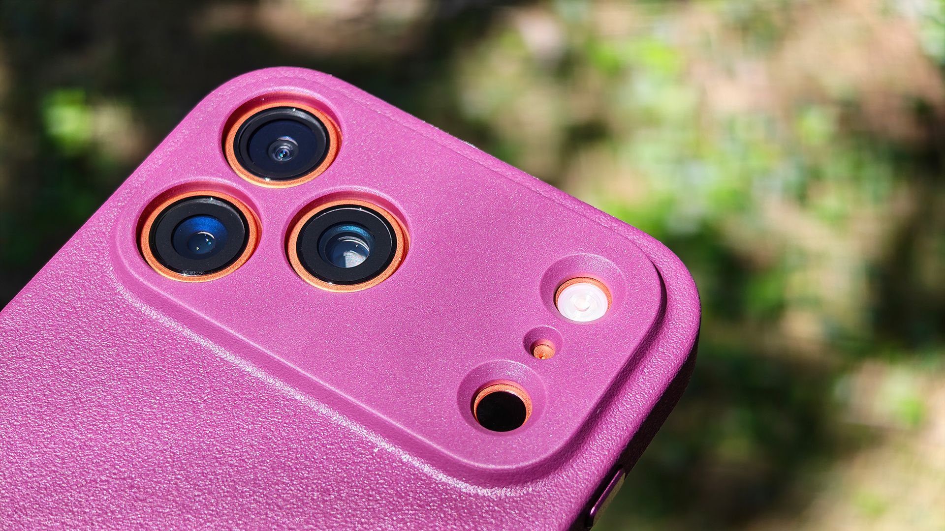 A burgundy Dbrand MNML case on an orange Apple iPhone 17 Pro Max
