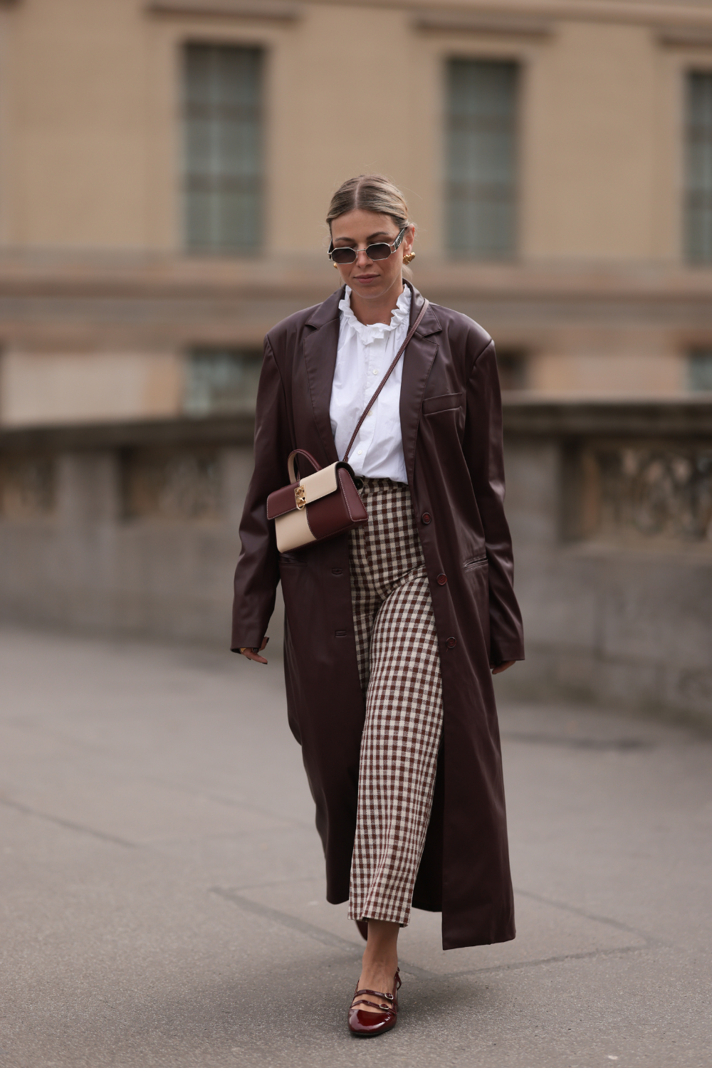 Aline Kaplan seen wearing Carolina Lemke gold sunglasses, gold earrings, S&amp;eacute;zane white cotton ruffled button blouse / shirt, S&amp;eacute;zane beige / brown checked long pants, YOOX burgundy leather long coat, Cafune beige / burgundy leather bag and S&amp;eacute;zane burgundy shiny leather heeled ballerinas