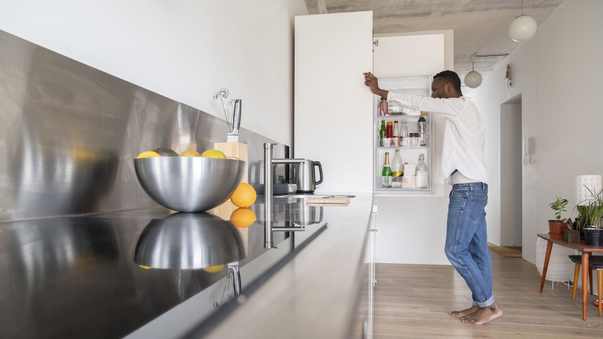 A man leans against a French door refrigerator