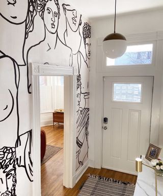 Entryway with figure design on the wall and white front door