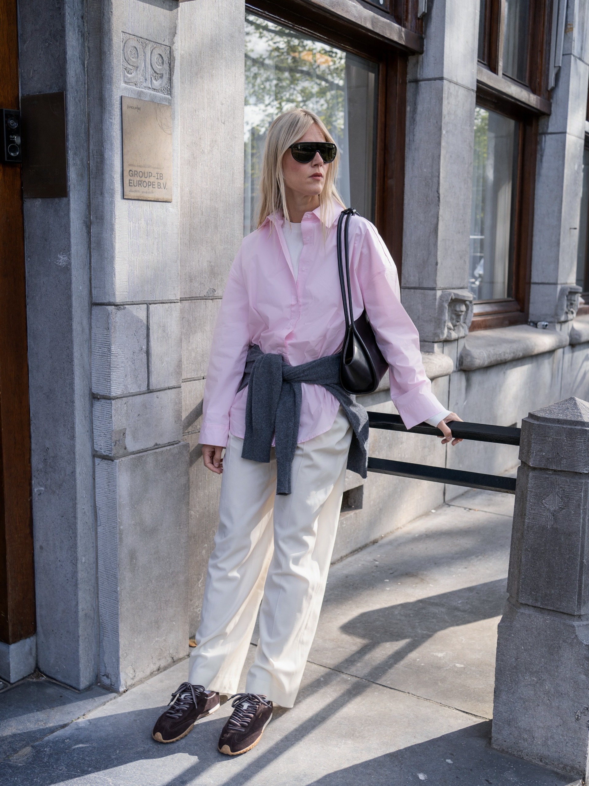 Influencer wearing a pink button-down, khaki pants, and brown sneakers
