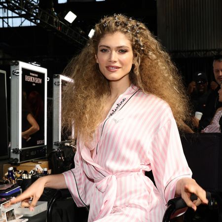 Valentina Sampaio wears a pink striped robe with teased hair backstage at the Victoria's Secret Fashion Show 2024