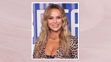 Image of Amanda Holden smiling with wavy blonde hair and wearing a leopard print blazer, on a lilac background