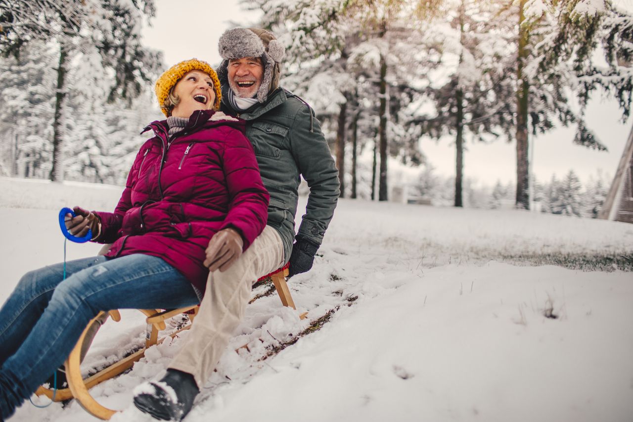 Older couple sleds in the snow.