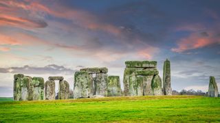 A pink sunset with clouds falls over Stonehenge in England.