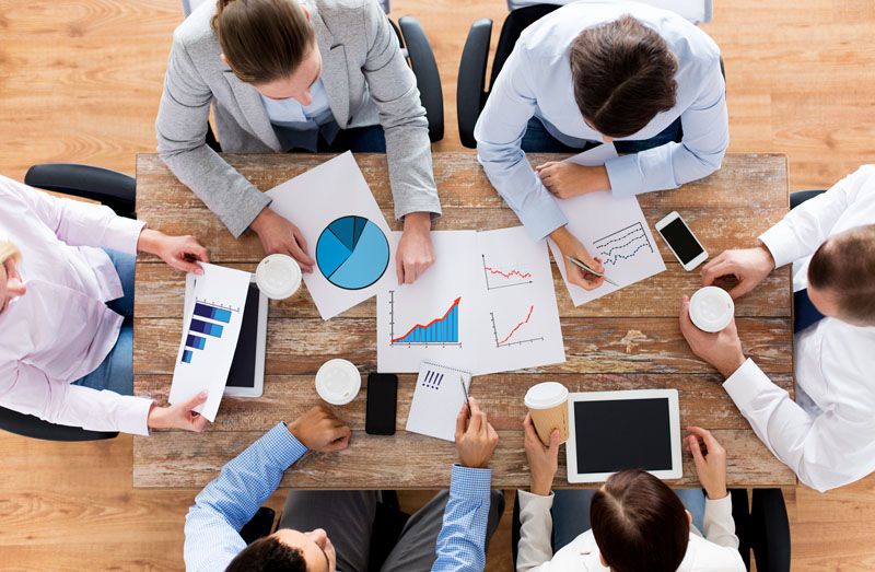 A group of people sat around a table discussing business data.