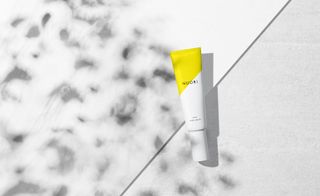NUORI skincare hand cream in white packaging with a yellow top photographed on a white background.