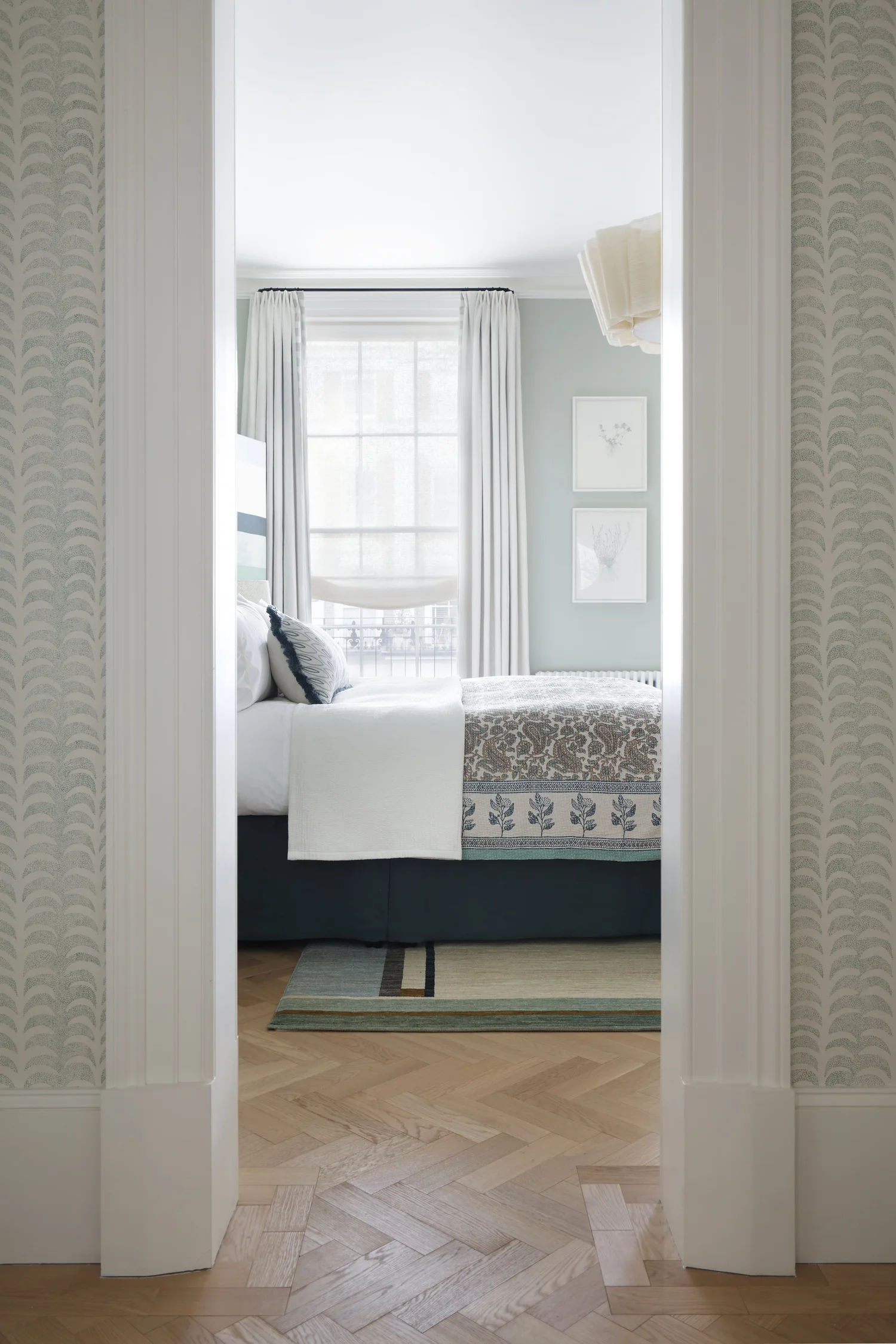 Airy pale-blue bedroom with patterned bedspread and parquet floor