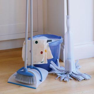 bucket with cleaning accessories on brown floor