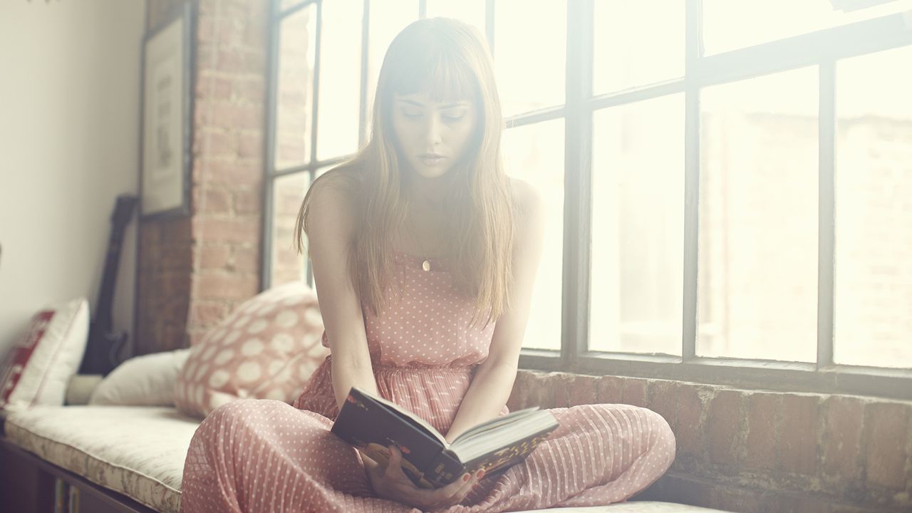 Young Woman reading book in apartment