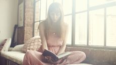 Young Woman reading book in apartment