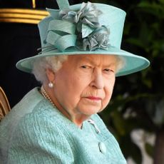 Queen Elizabeth glares while wearing a green suit and matching hat