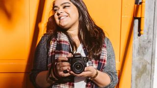 A woman holding the Canon EOS 200D Mark II