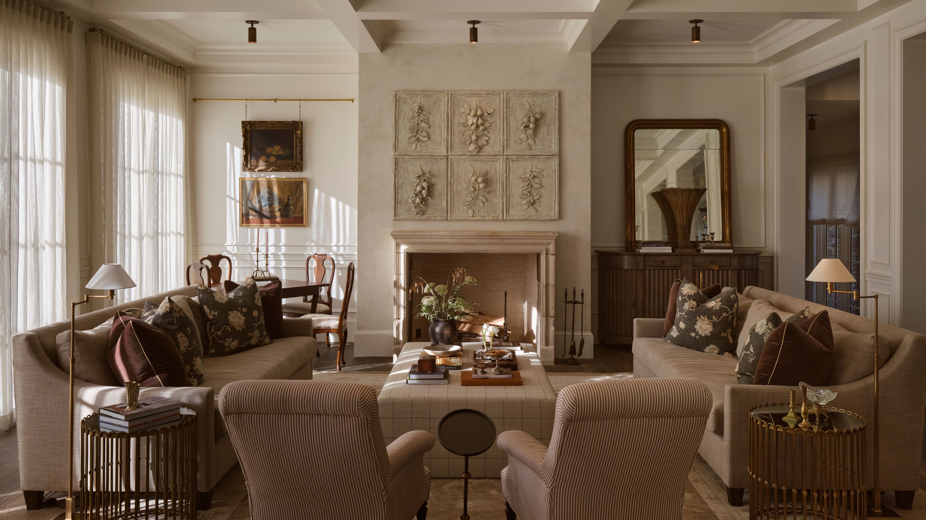 a layered neutral living room with coffered ceiling, stone fireplace, layered neutral earthy textiles and antique finds