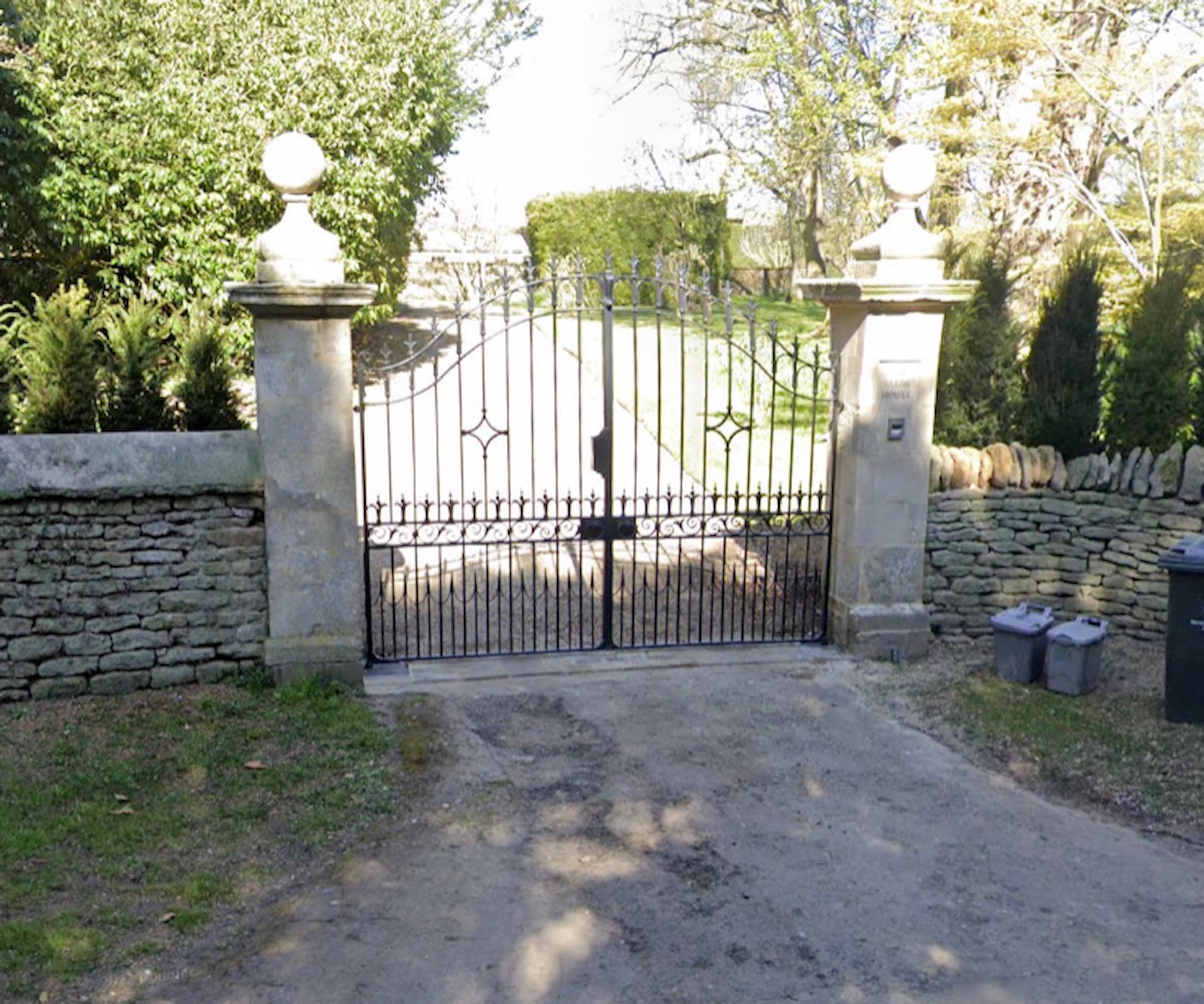 A set of gates next to a stone wall for a driveway