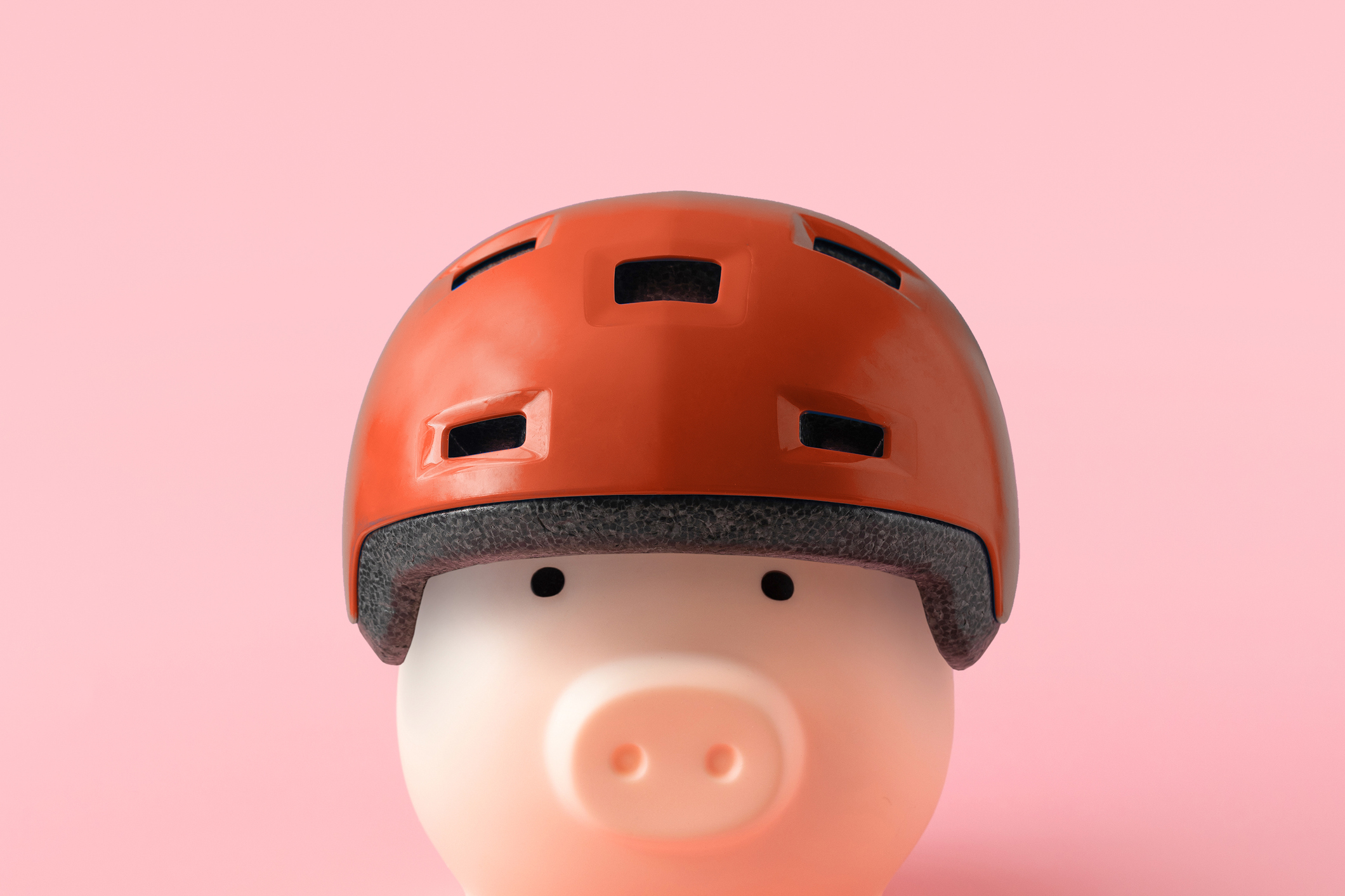 Piggy bank in a red helmet on a pink background. 