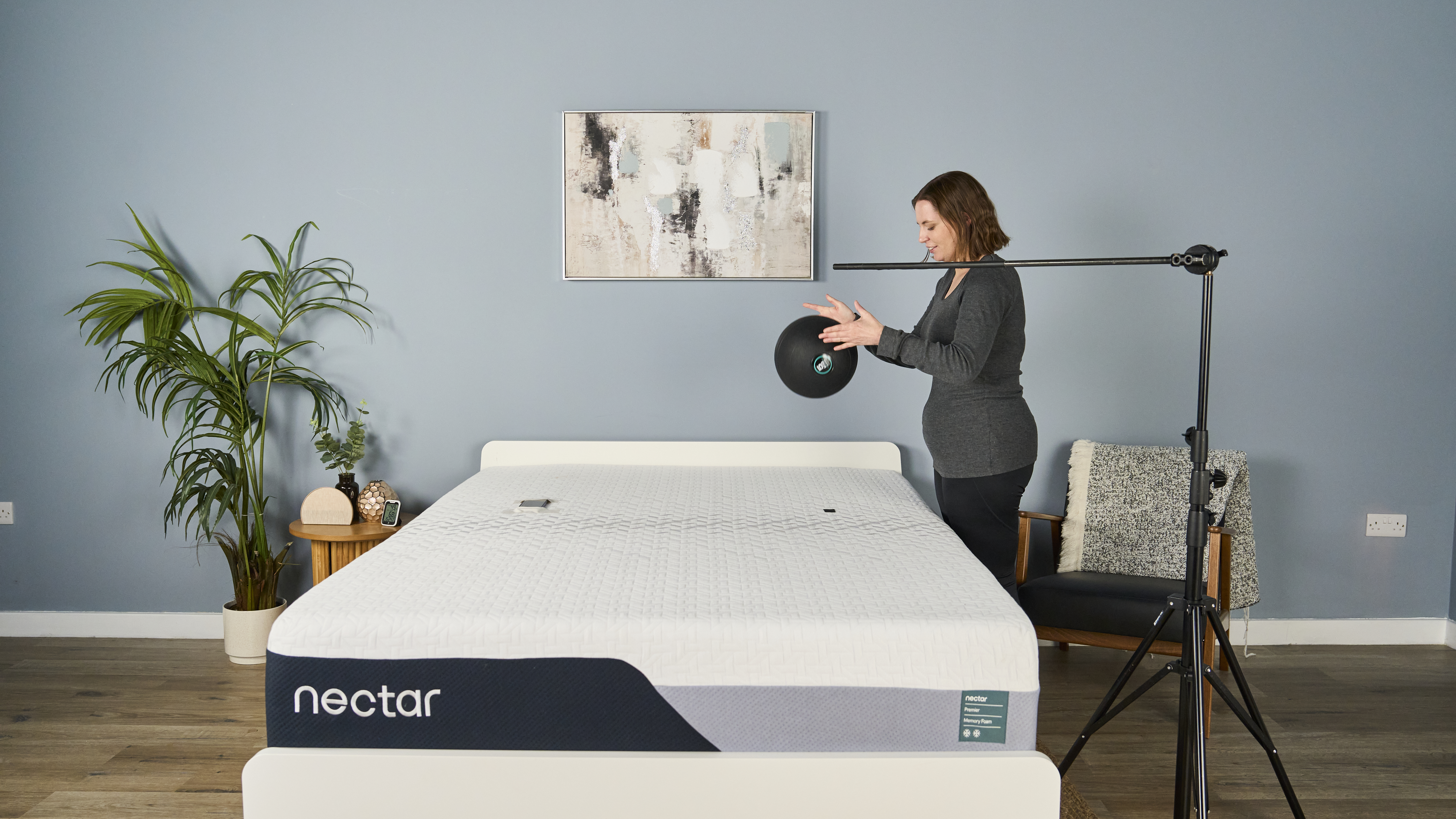 Tester Ruth Jones drops a slam ball on the Nectar Premier Memory Foam Mattress to measure its motion isolation. Two accelerometer are taped to the mattress to measure the ball's initial impact rate.
