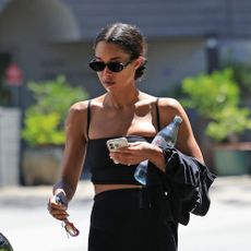 Laura Harrier wears bike shorts with black flip-flops and a black sports bra.