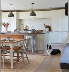 Kitchen with shaker style cabinets, wooden table and large jute rug with dog
