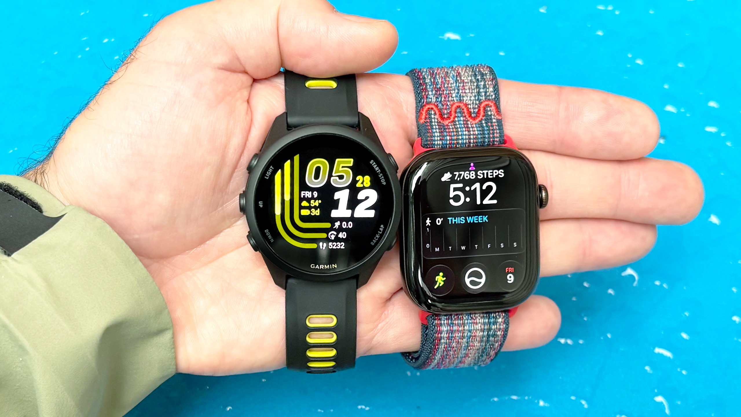 Close-up of the Apple Watch 12 and Garmin Forerunner in the writer's hand 