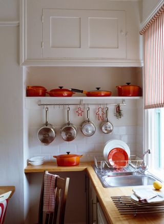 A kitchen with Le Creuset cast iron cookware on a shelf