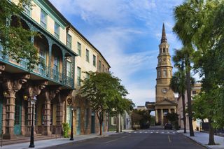 A street in Charleston with older buildings to the left and a church in the middle