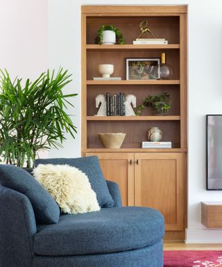 Detail of a living room with a blue armchair and tall wooden sideboard
