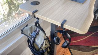 Headphones and a backpack hanging from the Vari Ergo with provided hooks