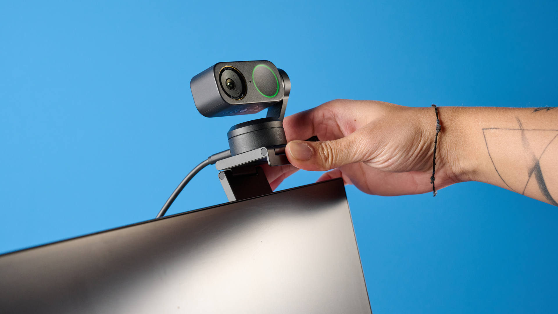 Insta360 Link 2 Pro in graphite black attached to a computer screen photographed on a blue background