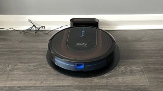 Eufy RoboVac G30 Hybrid on its charging stand on a wooden floor