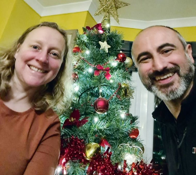 Alison Wainwright and Helder smile by a Christmas tree