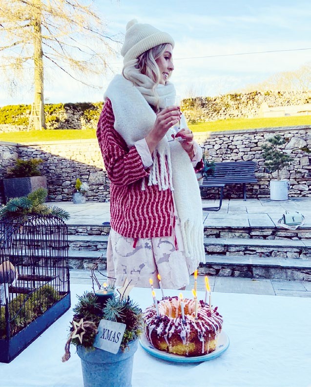 Poppy standing outside, wrapped up warm, with a birthday bundt cake