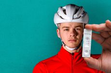 Joe Baker standing holding up his positive Covid test close to the camera