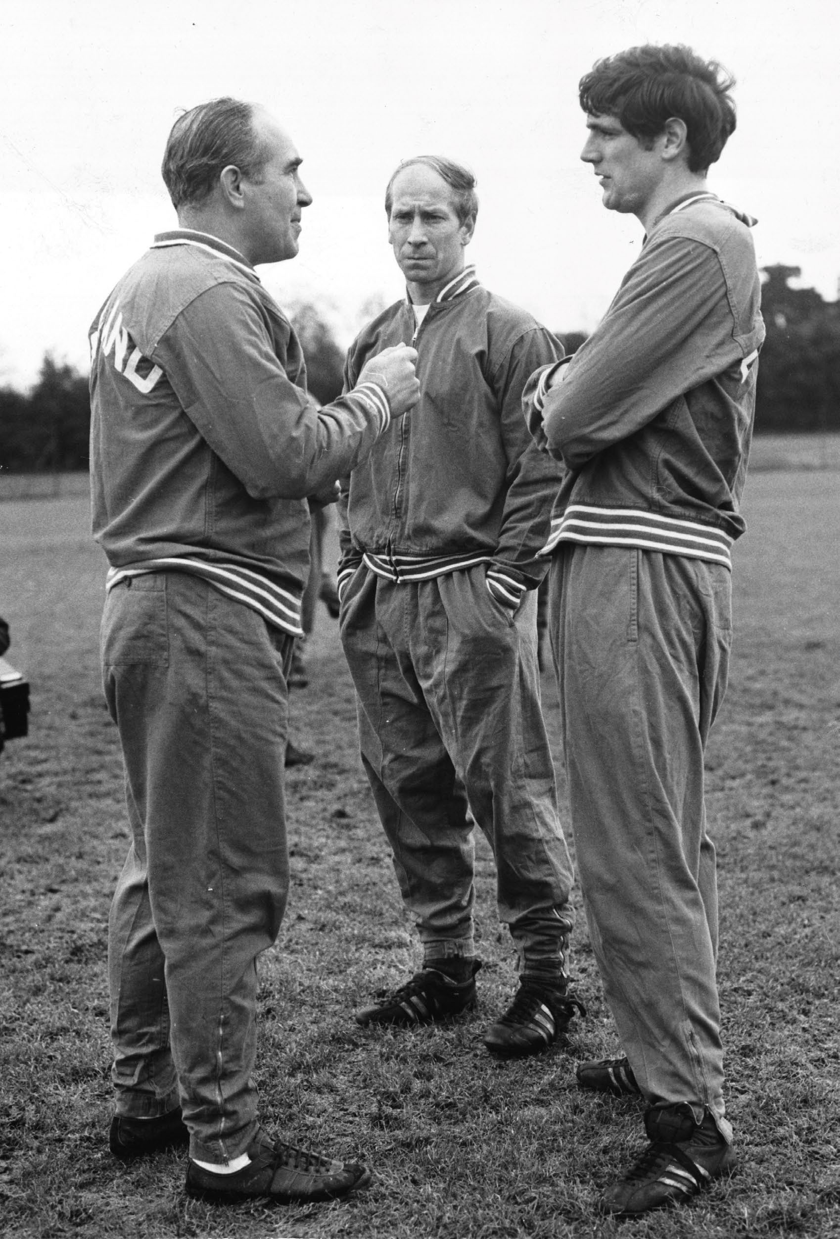 (Original Caption) England players train for Rumanian match. England players were at the Bank of England's ground, Roehampton, today, training for tomorrow's friendly match against Rumania, at Wembley tomorrow night. Photo shows: Sir Alf Ramsay, England team manager (left), makes a point with Norman Hunter, whilst Bobby Charlton (centre), listens. (Photo by &amp;copy; Hulton-Deutsch Collection/CORBIS/Corbis via Getty Images)