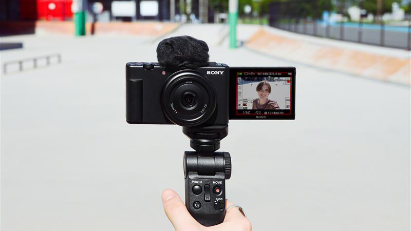A hand holding the Sony ZV1-F camera on a mini tripod