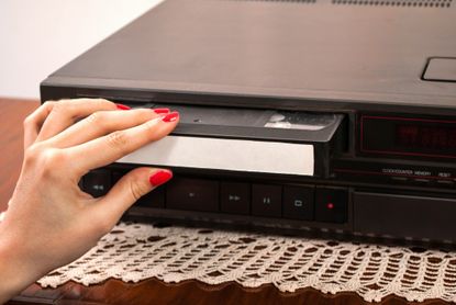 VHS player with someone inserting a video tape