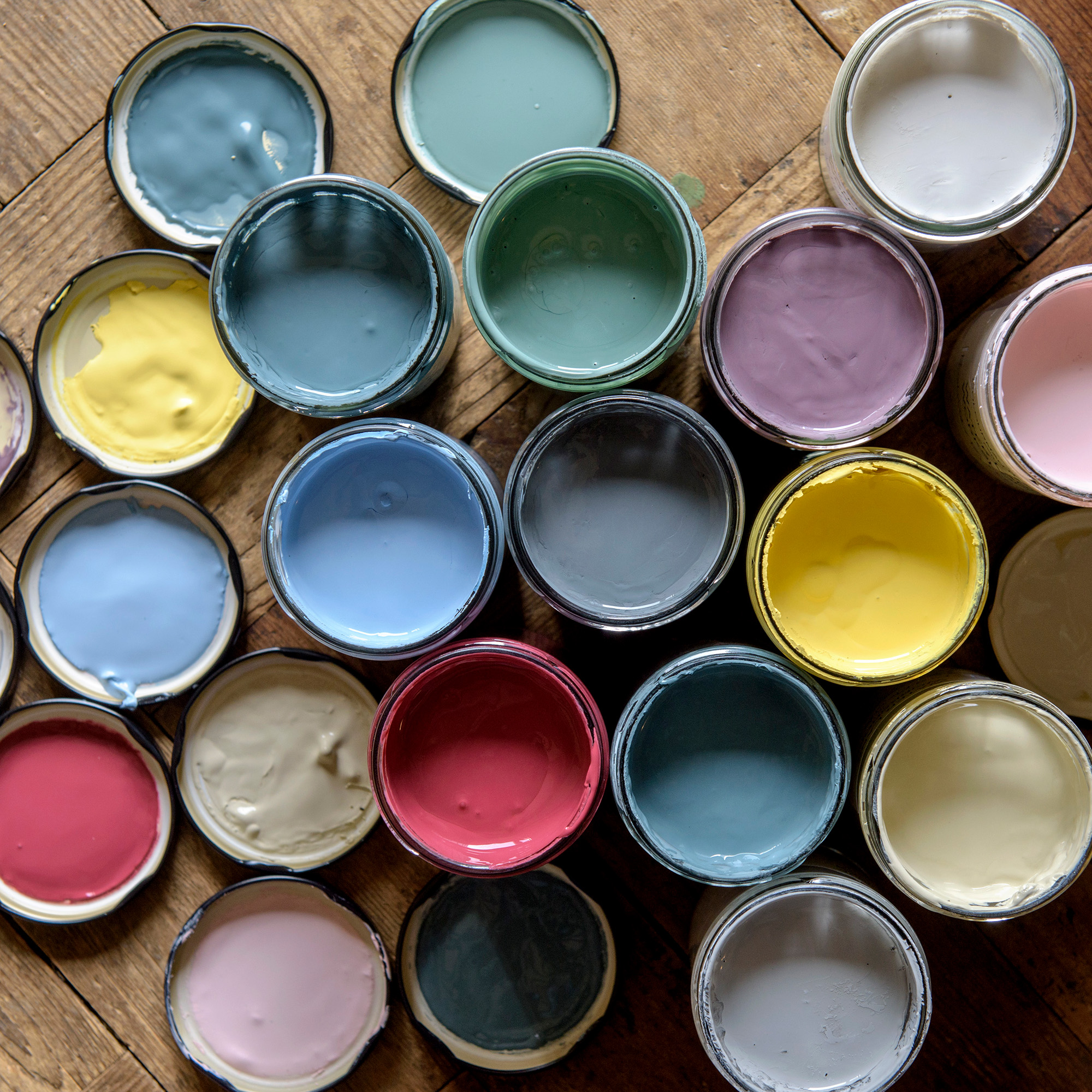 multicoloured jars of paint with lids on a wood floor
