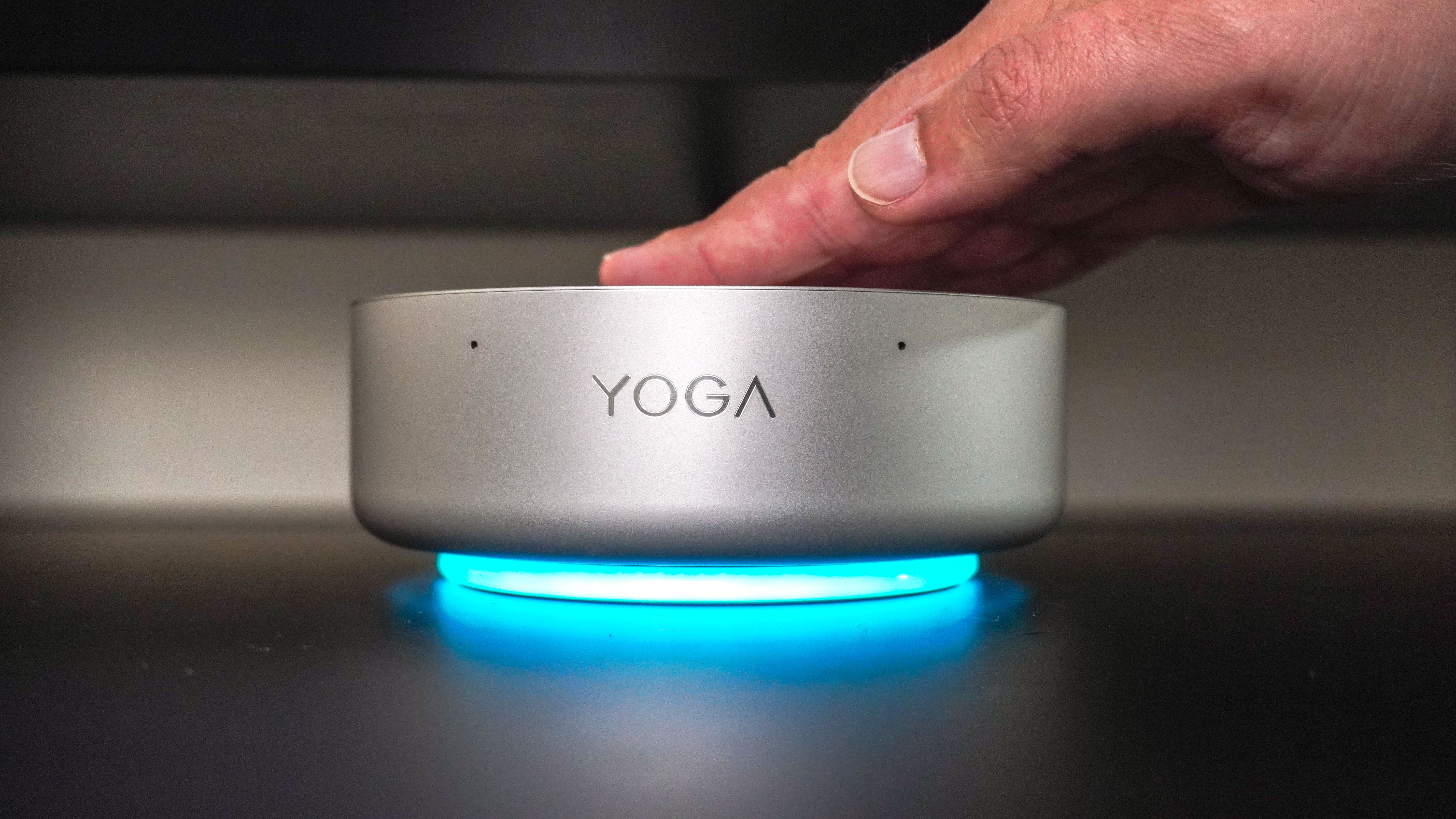 A person tapping the top of the Lenovo Yoga Mini mini PC