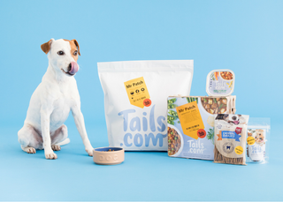 Tails dog food on blue background with dog posing