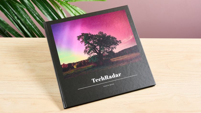 The Once Upon photo book is displayed on a tabletop. The cover is a satin-finished black, with a large image of a tree in front of a colorful aurora sky.